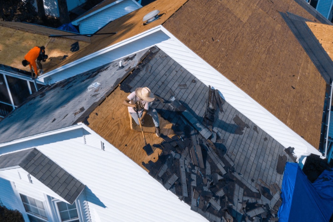 Aerial view of a roofing crew tearing a shingle roof down to the decking